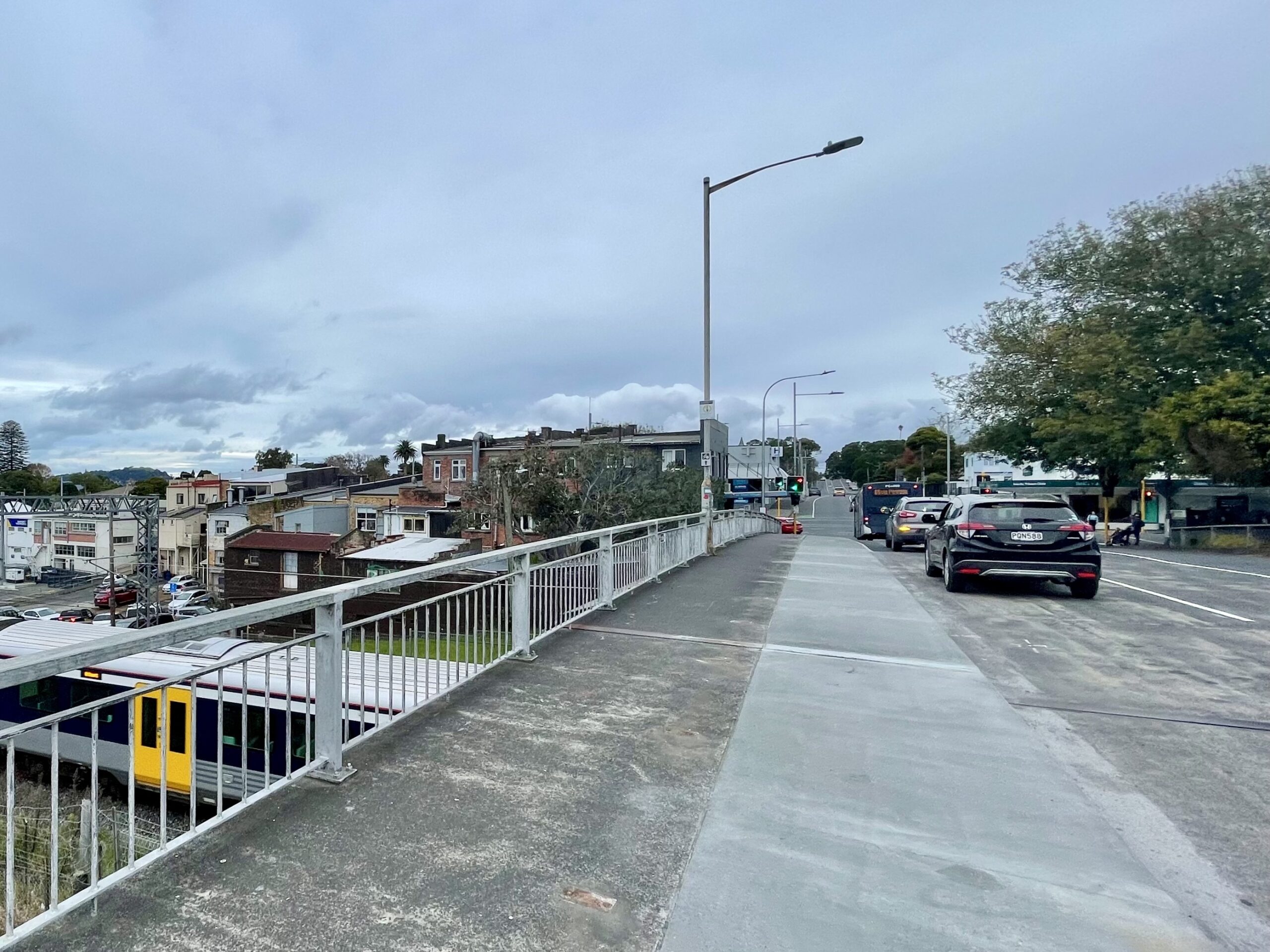 A newly widened pathway on the Mt Albert rail over bridge. There is a train visible passing under the bridge.