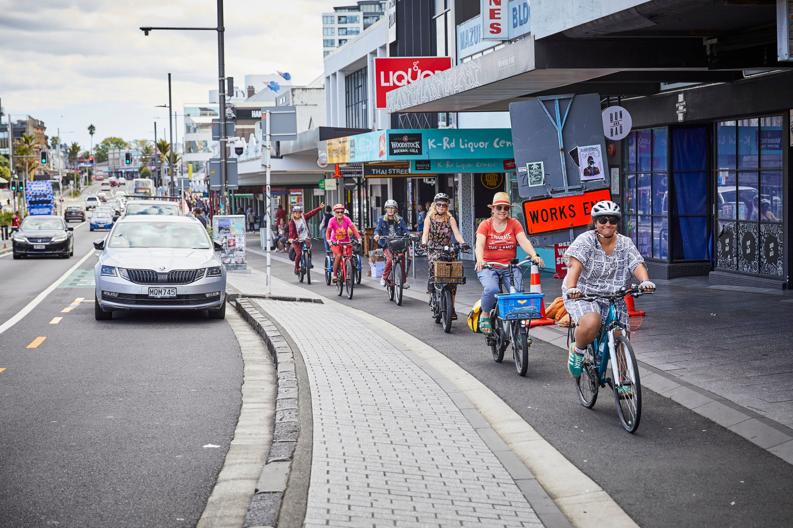 Several people riding bikes in the cycleway along Karangahape Road.