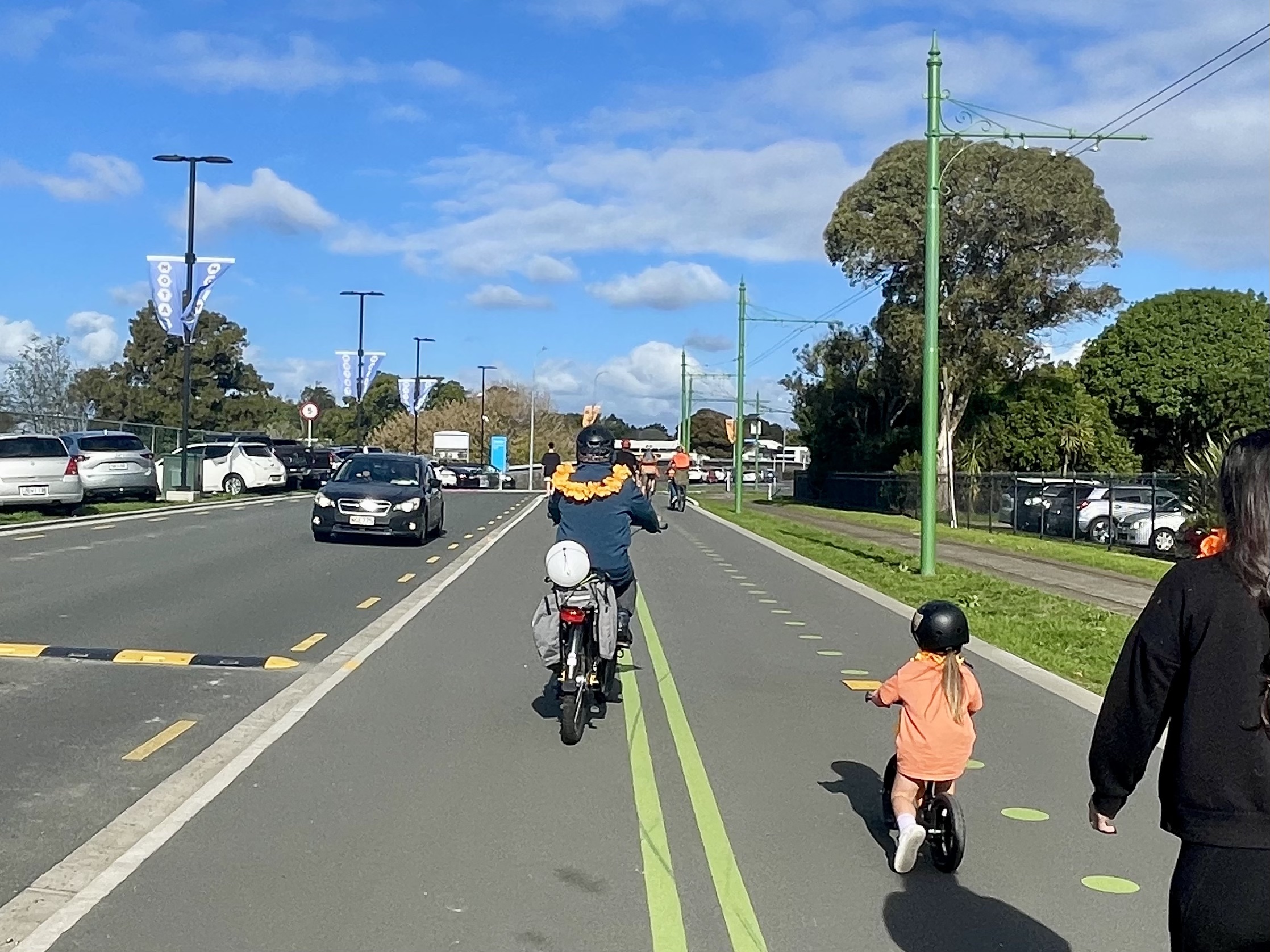 Children and their guardians ride bikes along a wide pathway