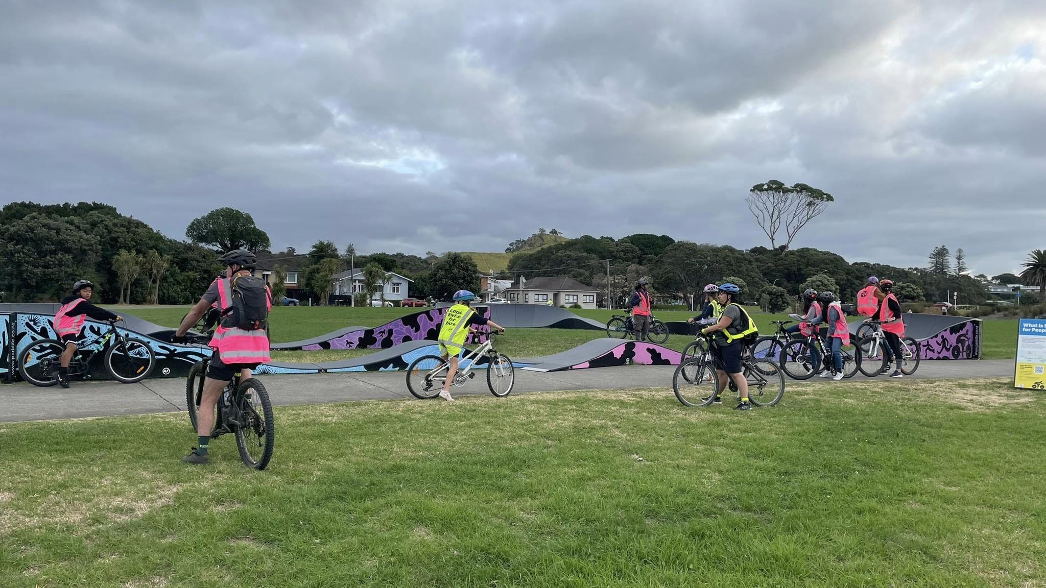 Photo: Multiple high-vis vested people on bikes are visiting the Waterfron Reserve temporary pump-track. 