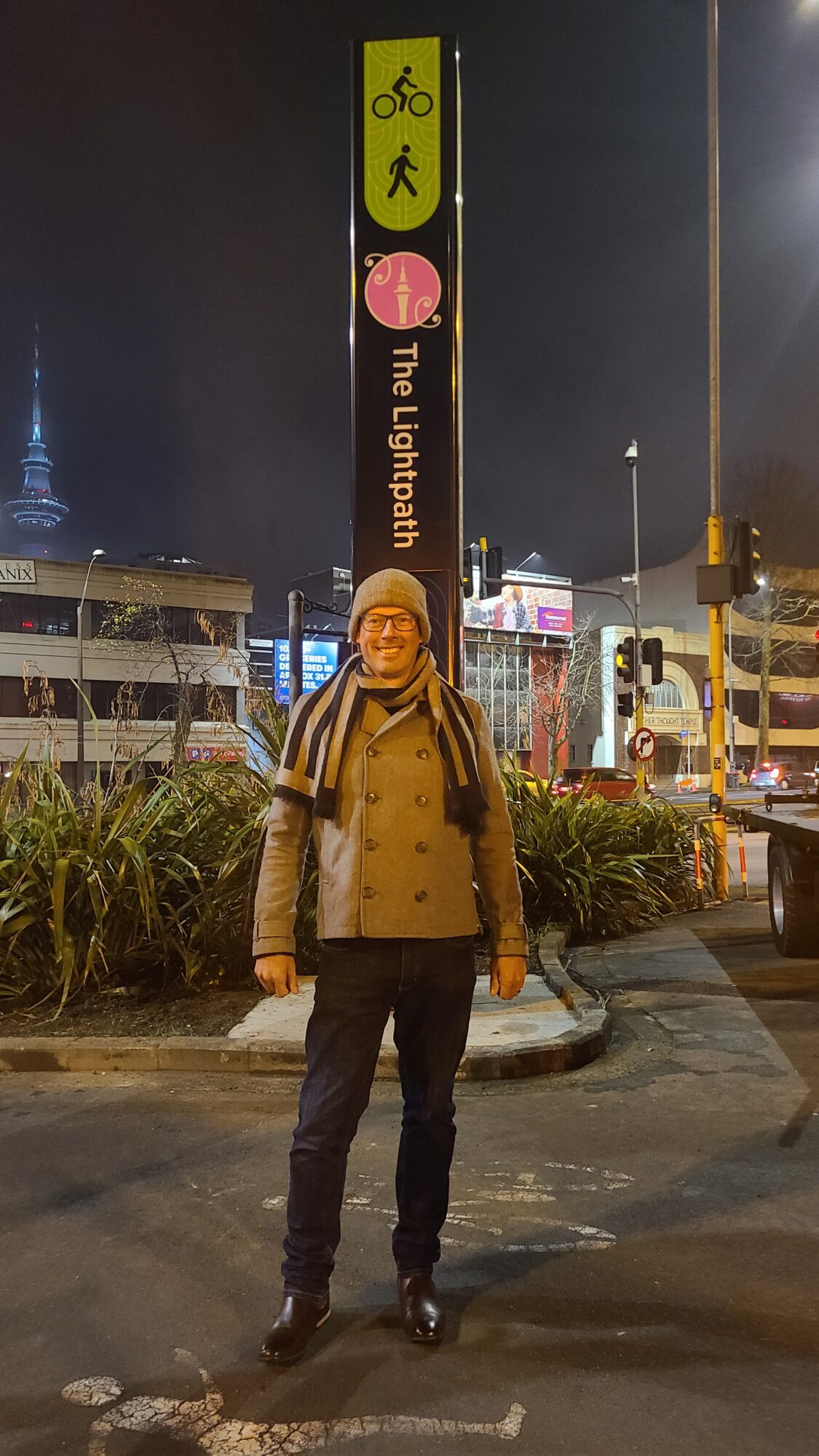 Mark stands proudly beside a lit wayfinding beacon on the City Centre Loop at nighttime