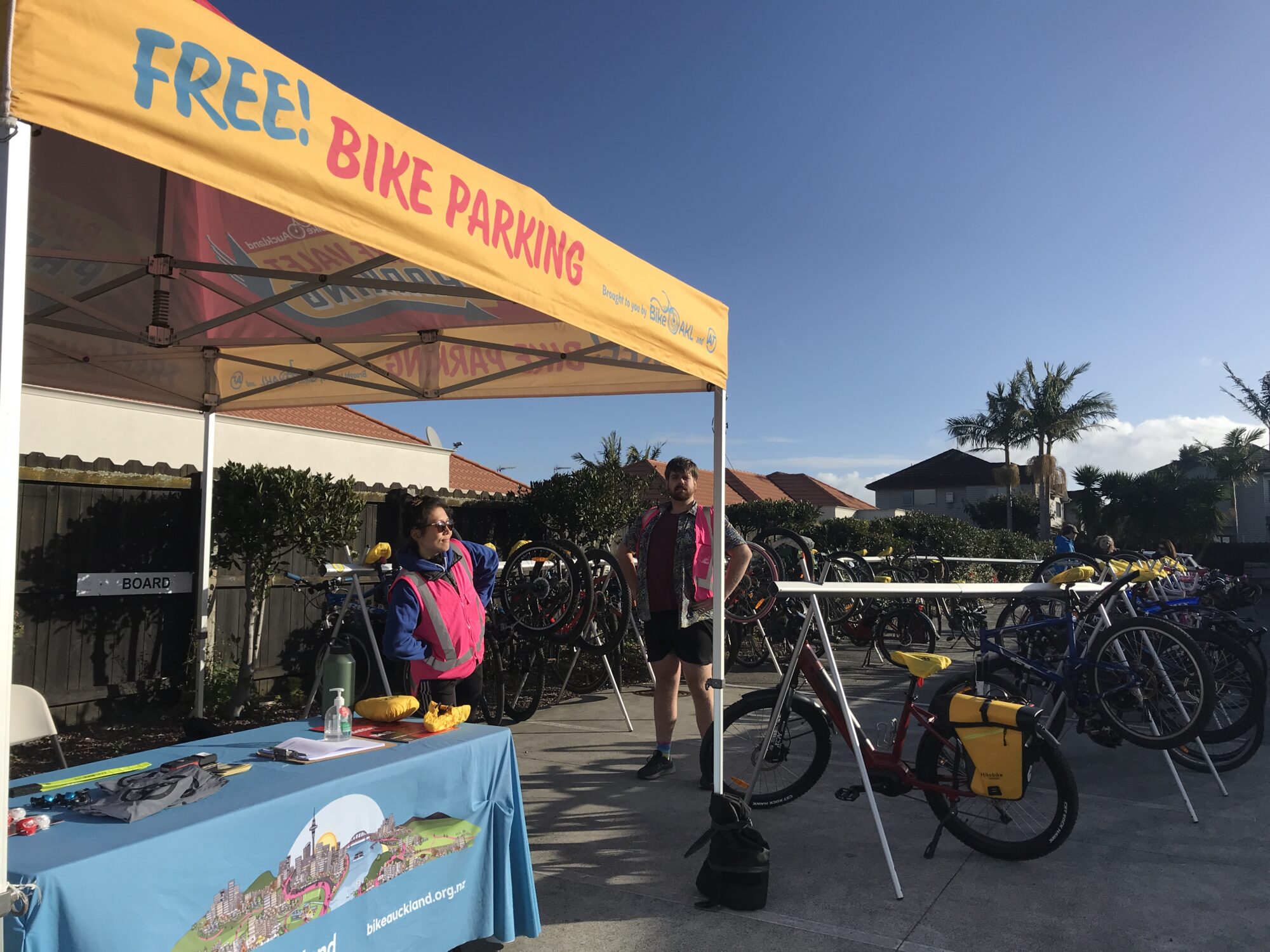 The Bike Valet desk and lines of bikes on racks with Angie and Cappuccino in high vis vests