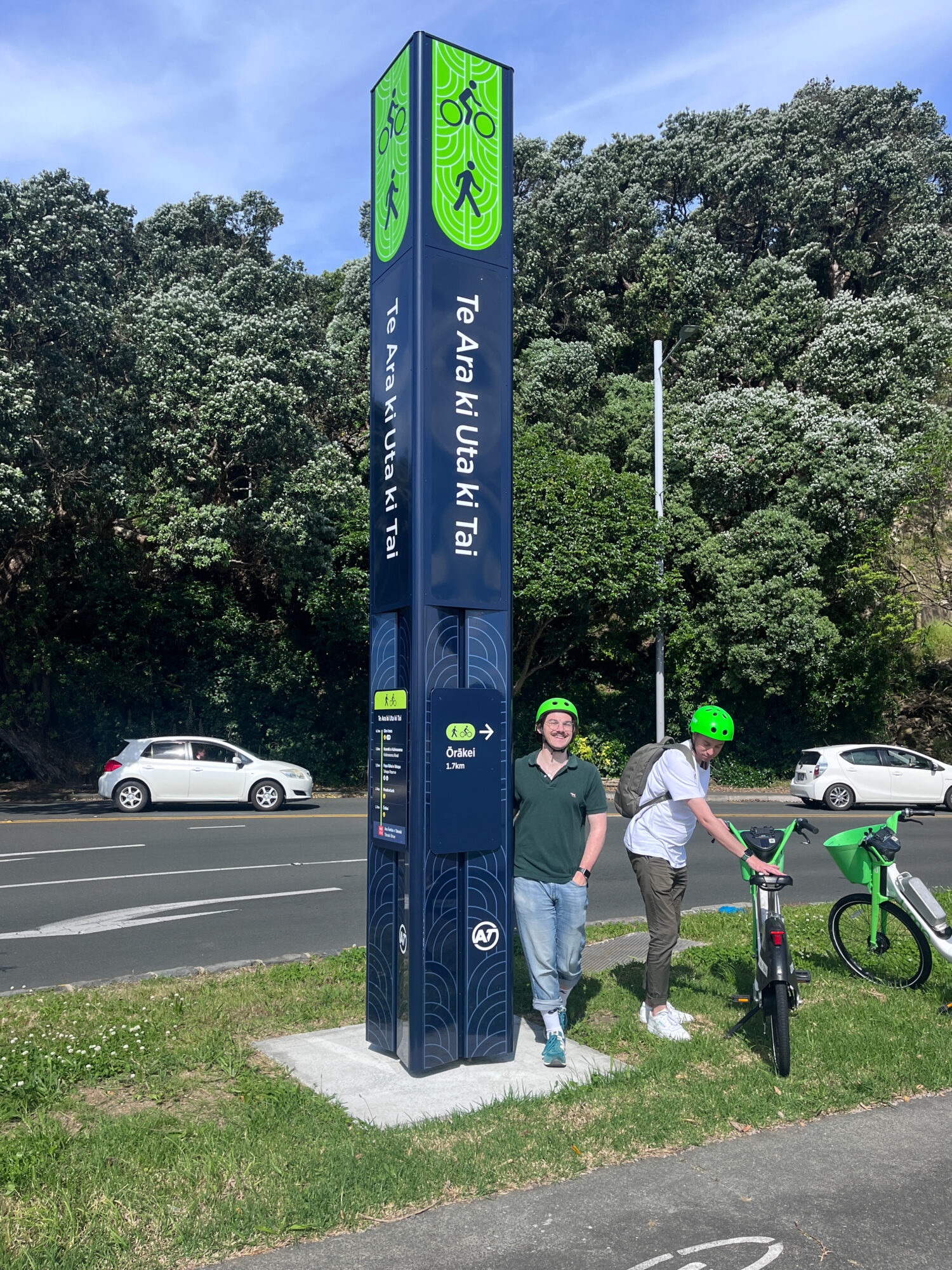 Sam and a colleague pose with a beacon - a prominent tall column of wayfinding signage  