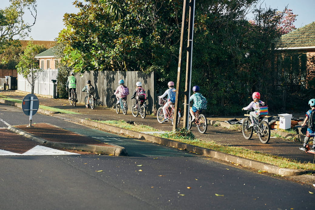 Led by an adult guide, a group of six or so kids on bikes head up a footpath