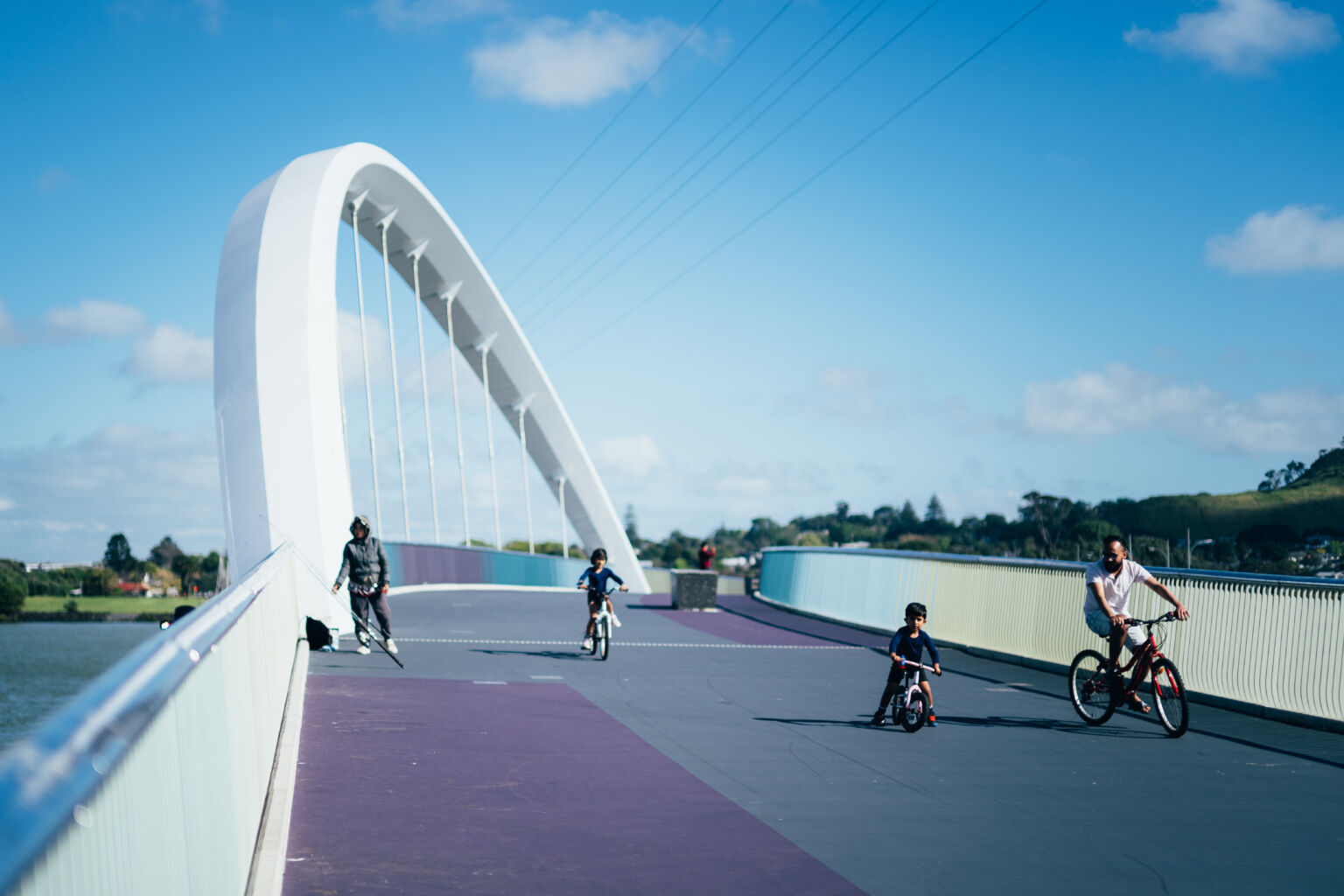 A family rides across a sculptural modern bridge