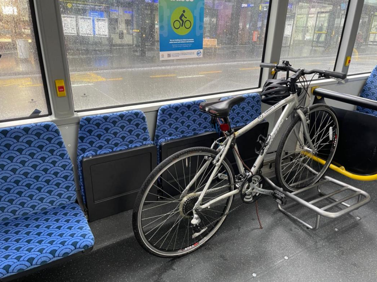 A bike on a bus with 2 folded up seats behind it