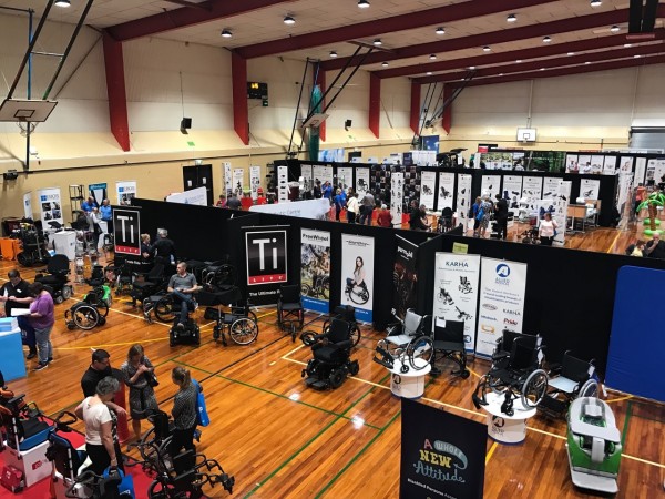 An expo hall with lots of people and some wheelchairs