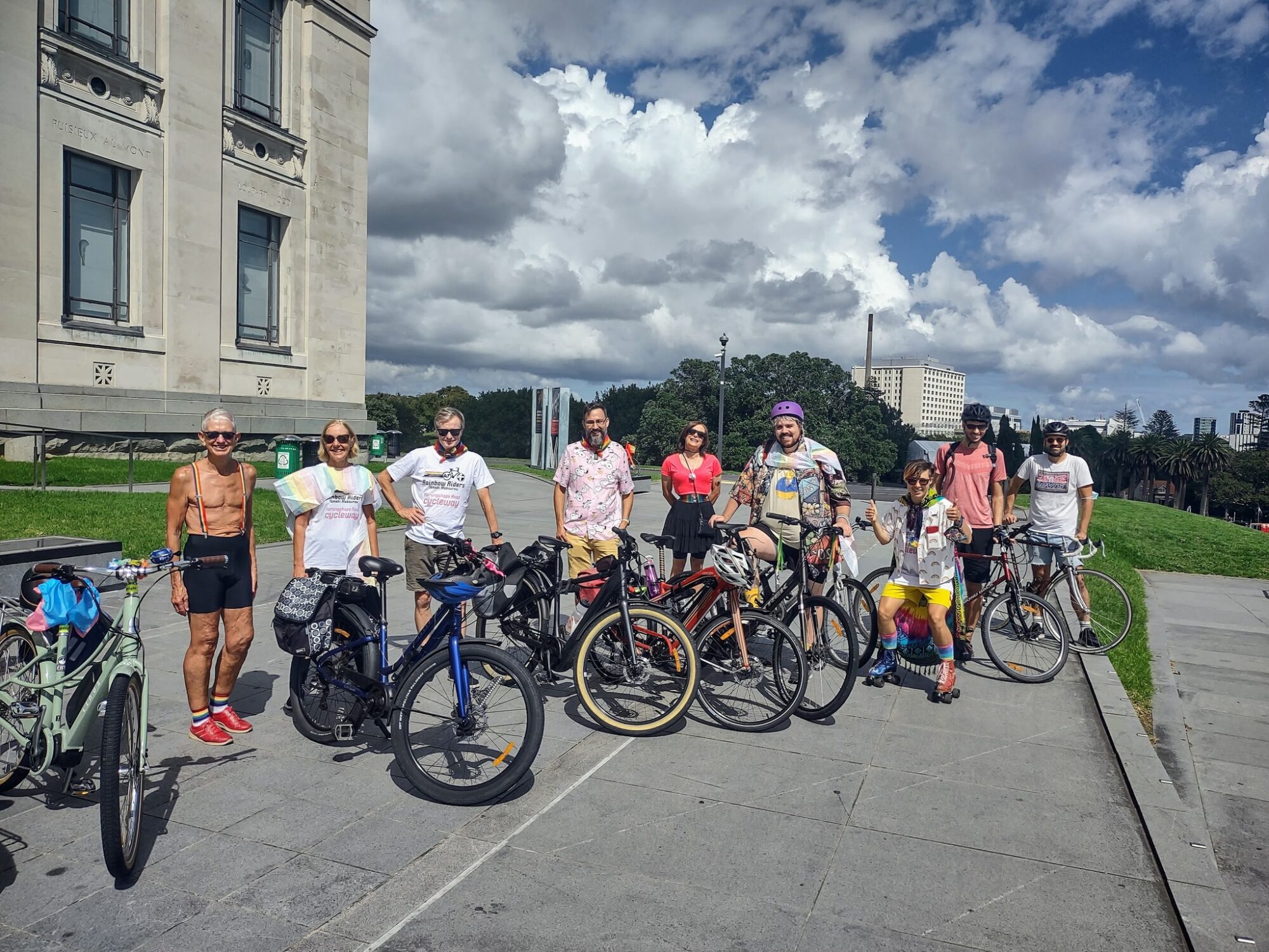 A group of people with their bikes, wearing rainbow attire